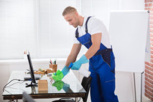 Janitor Cleaning Desk With Cloth In Office
