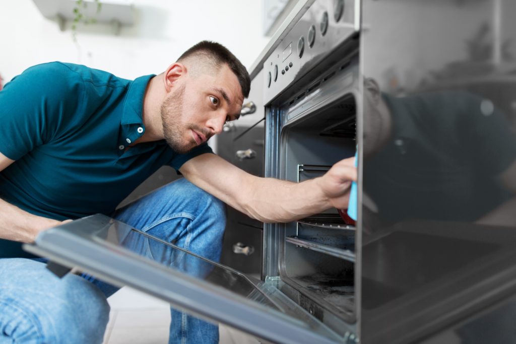 man cleaning inside the oven